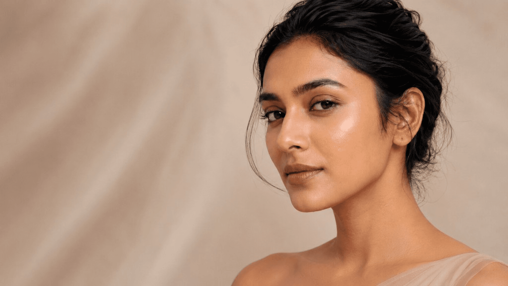 An Indian woman with soft, hydrated skin in warm neutral light