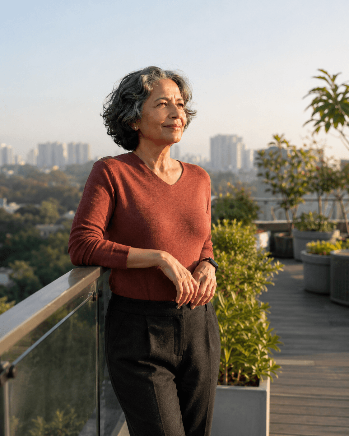 A confident Indian woman with natural silver hair in a rooftop garden